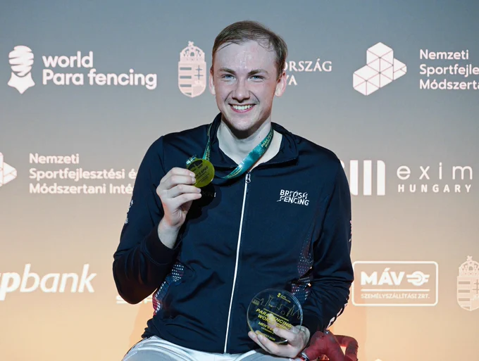Piers Gilliver smiles to the camera while wearing a gold medal.