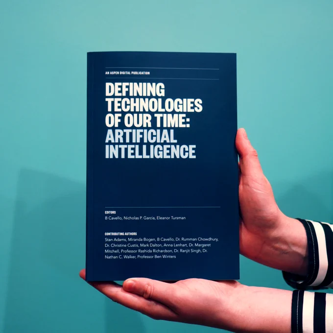 Hands holding a book titled, "Defining Technologies of Our Time: Artificial Intelligence."