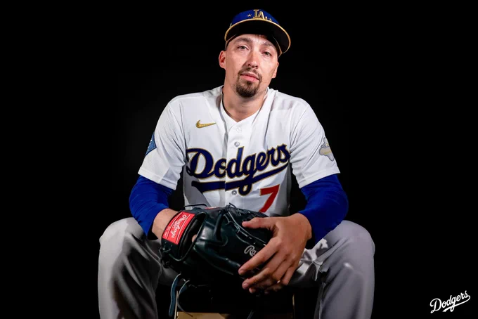 A photo of Blake Snell holding his glove and looking at the camera while wearing his Dodgers gold jersey.