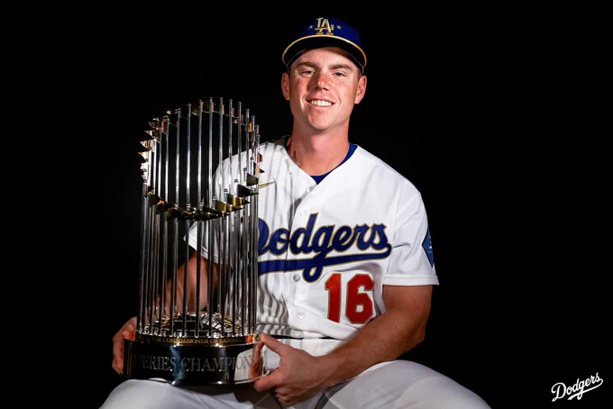 A photo of Will Smith wearing the Dodgers gold jersey while holding the World Series trophy.