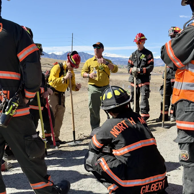 Image of firefighters receiving instruction in a dry grassy field