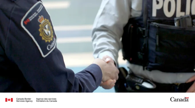 A CBSA officer shakes hands with an RCMP officer.