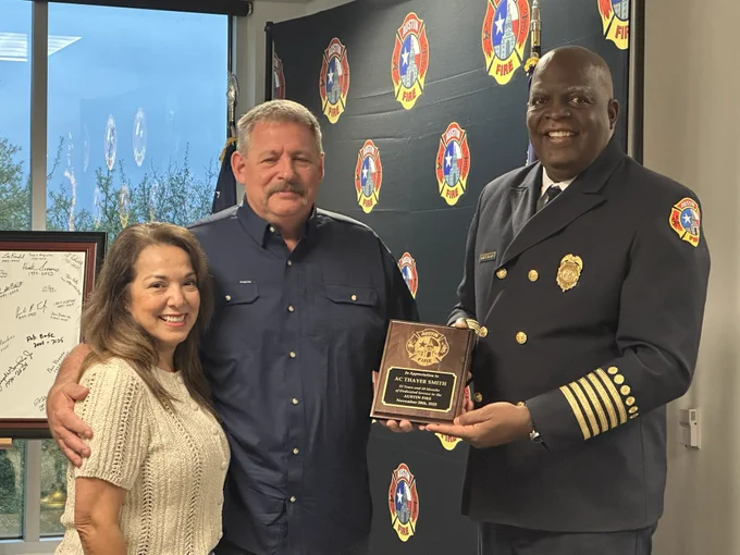 Chief Smith stands between his lovely wife and Chief Baker while receiving a plaque.
