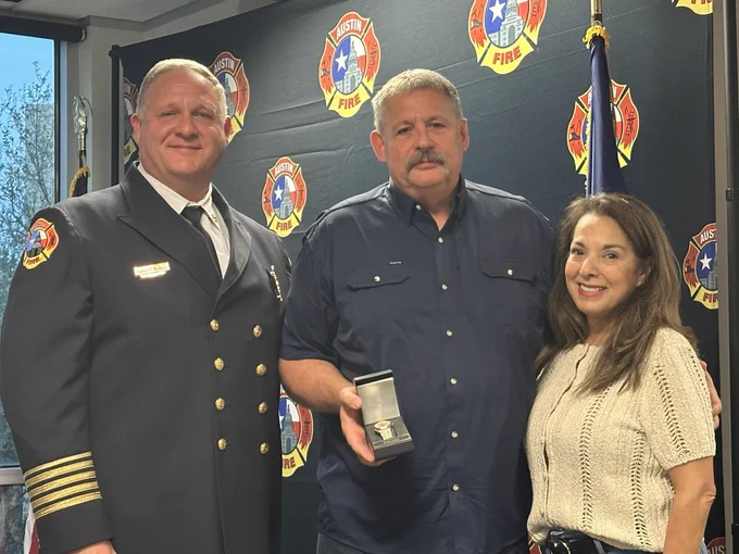 Chief Smith stands between his lovely wife and Chief Vires while receiving a plaque.
