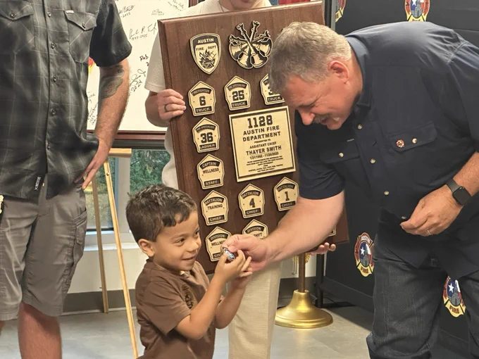 Chief Smith is seen looking at a challenge coin being held by a young boy.
