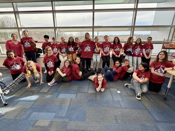 The Hughes battle of the books team post together in their team T-shirts in the library.