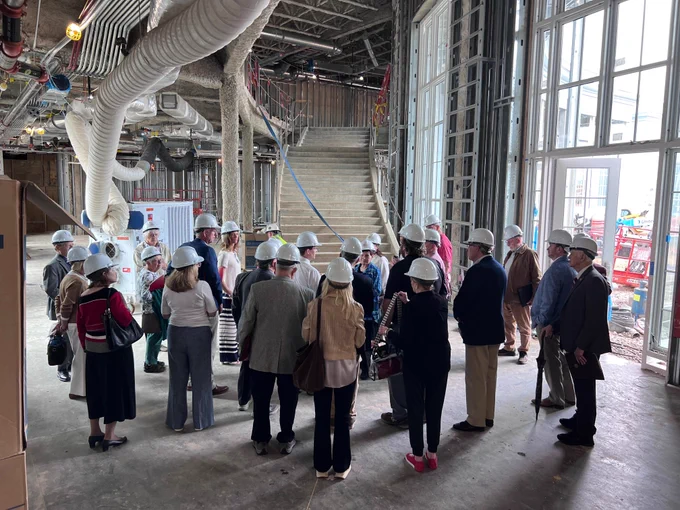 Several BCAS board members in hard hats touring an indoor construction site. 