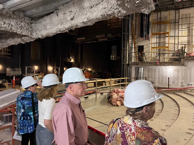 Several BCAS board members in hard hats touring an indoor construction site. 