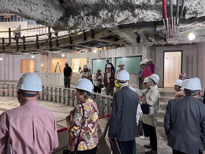 Several BCAS board members in hard hats touring an indoor construction site. 