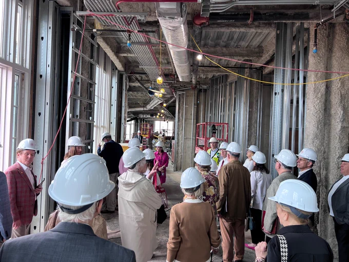 Several BCAS board members in hard hats touring an indoor construction site. 