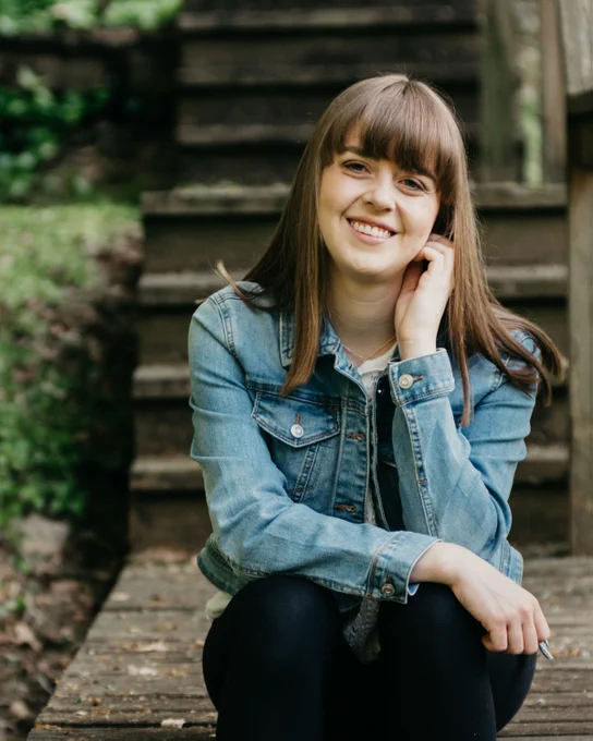 Graduate student Claire Southard ’25 sits in front of a set of dark stone stairs.