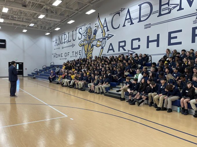 Secretary Aguilar speaks to students sitting in bleachers in school gymnasium, shot shows group of students from other side of the gym