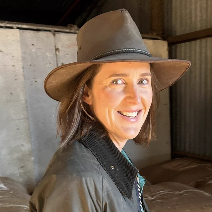 WA export fodder grower and rural journalist Olivia Thorn wearing a brown wide-brimmed hat and a weathered jacket inside a rustic barn setting. Post announcing her as an AgriFutures-sponsored participant in the 2026 ARLF TRAIL program.