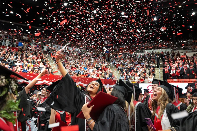 Smiles all over for graduates in black gowns while crimson and gray confetti falls from the ceiling of Beasley Coliseum during the 2024 Spring Commencement on the campus of Washington State University Pullman, Saturday, May 4, 2024.