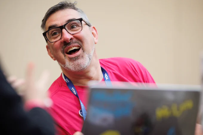 Photo of a man smiling while looking at something off camera. 