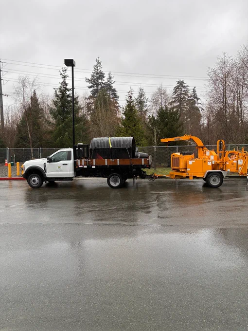 A City of Bothell Public Works truck with stormwater piping and a woodchipper in tow. 