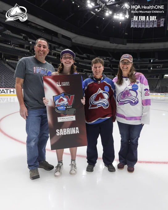 Av for a Day Sabrina on the Ball Arena Ice with her Av for a Day board with members of her family