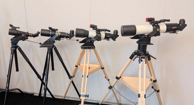Tele Vue telescopes on tripods lined up against a wall.
