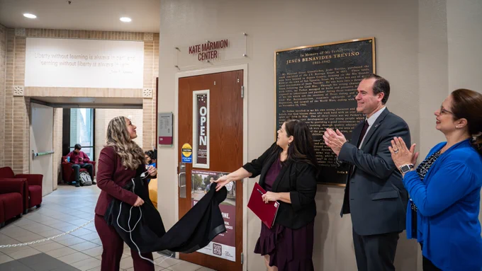 A banner unveiling of the "Kate Marmion Center" with individuals clapping and other's admiring the sign as it's unveiled.