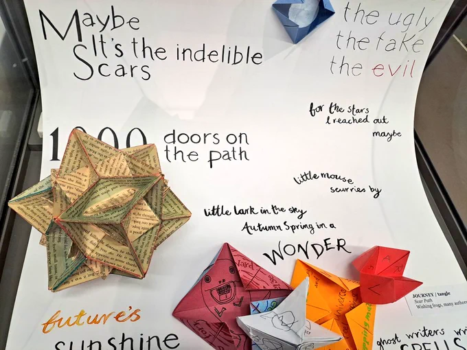 Poetry and colourful origami shapes on white paper background 