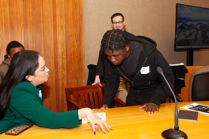 A 2026 Youth Law Fair volunteer helps a student participant in the mock trial. 
