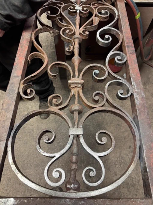 Hot forged wrought iron sections were carefully "let in" where material was wasted beyond 50% of its original thickness or where deemed structural. Reoplica scrolls and leaves were reintroduced only where full original examples were available to copy. 