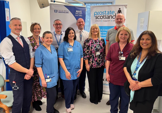 Group of healthcare professionals standing together in a clinic with NHS and Prostate Scotland banners in the background.