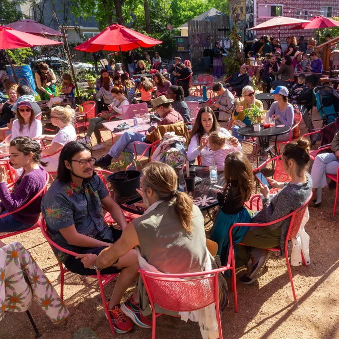 A large group of people sitting at tables outside at the Butterfly Bar at the Vortex in Austin, Texas.