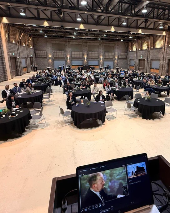 From the stage view, looking down at the audience, with a laptop on the podium showing the slideshow slides.