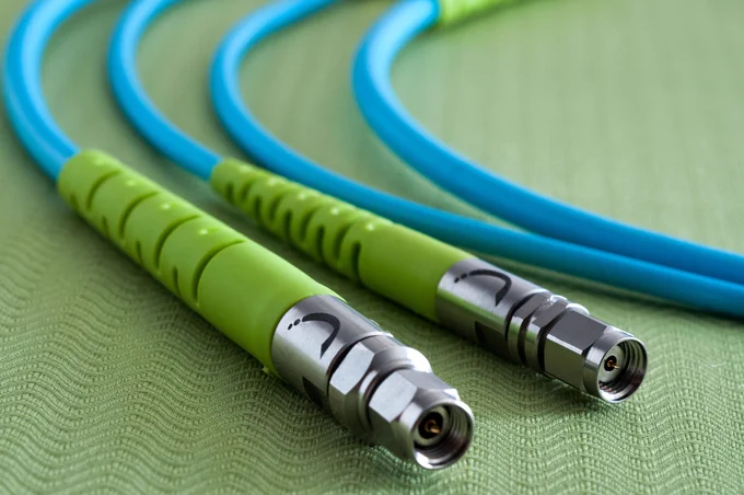 Two blue and green Swift Bridge Technologies FastEdge RF cables rest on a textured green surface.