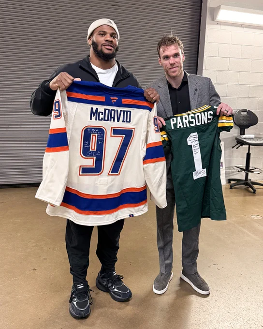 Micah Parsons of the NFL's Green Bay Packers holds up a signed Connor McDavid jersey next to McDavid who's holding up a signed Parsons jersey after the game in Dallas