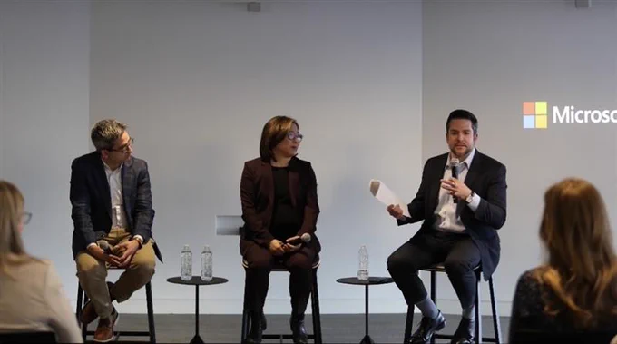 Oren Cass, Portia Wu and Gerry Petrella sit at the front of a room speaking on a panel with the Microsoft logo in the background