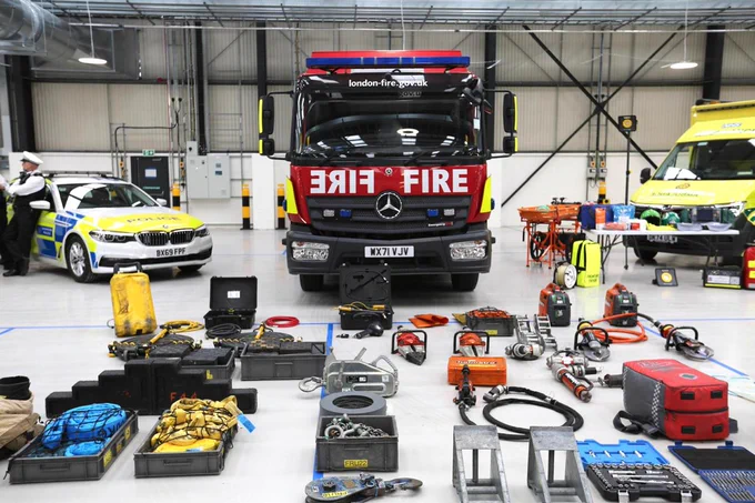 A fire engine, police car and ambulance and equipment laid out indoors