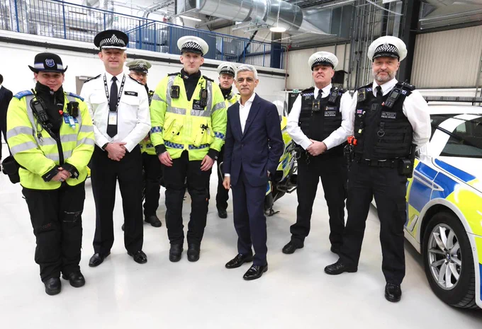 Mayor Sadiq Khan stands with seven police officers next to a police car