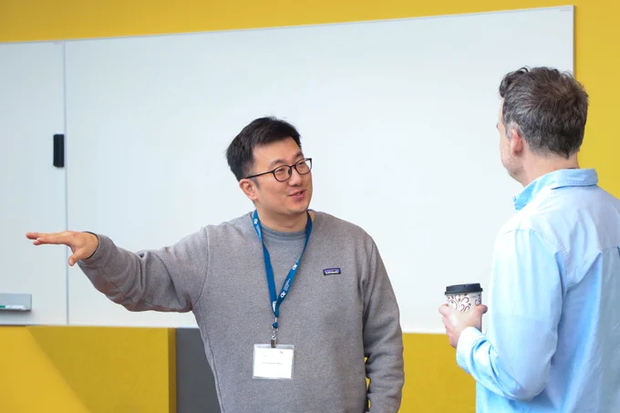 Two men talking to each other. The man on the left is gesturing with his hand.