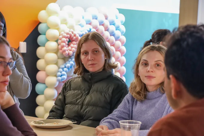 Two female students looking out of frame to someone talk with them.