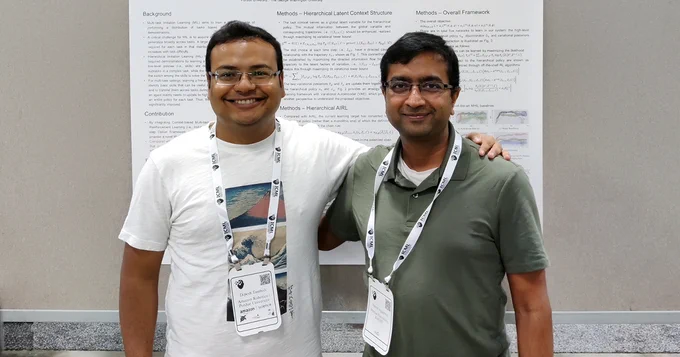 Dipesh Tamboli (left) and Vaneet Aggarwal (right), researchers from Purdue University, stand smiling in front of an academic research poster at the ICML conference. Both wear conference lanyards. The poster behind them details their work on hierarchical imitation learning and privacy-preserving AI methods. Tamboli's conference badge identifies him as being affiliated with Amazon Robotics and Purdue University.