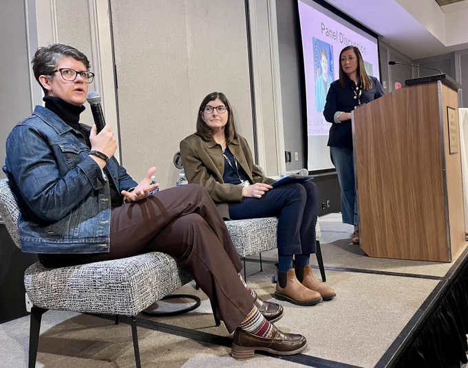 Dr. Jill Underly speaking while National Council for the Social Studies Executive Director Kelly McFarland Stratman, Sarah Kopplin of Shorewood High School look on.