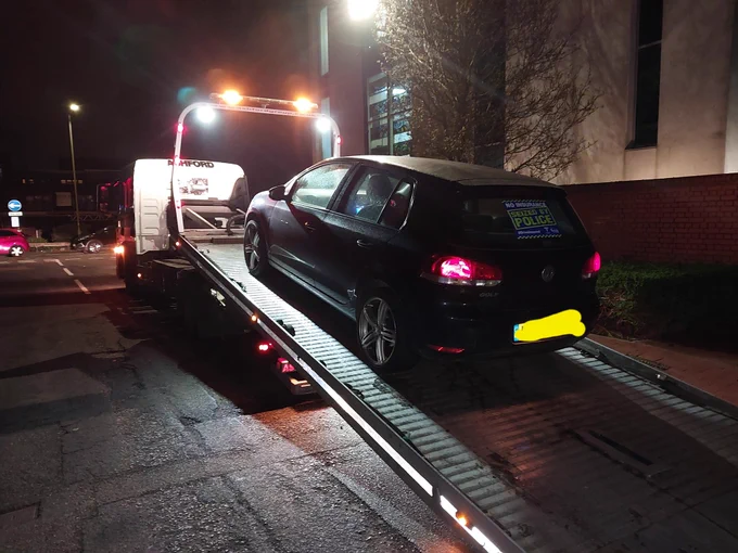 Uninsured and untaxed car with 'seized by police' sticker on window, on recovery truck