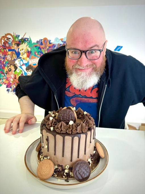 Simon smiles over a cake decorated with jaffa cakes.