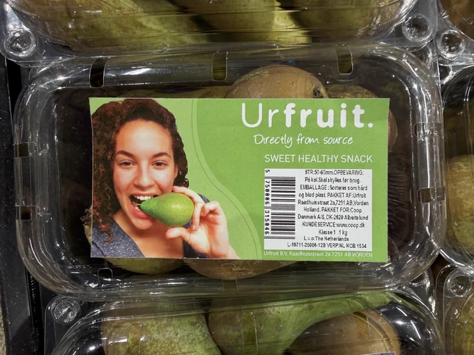 Photo of a woman missing a finger eating a pear from the side of the stem.