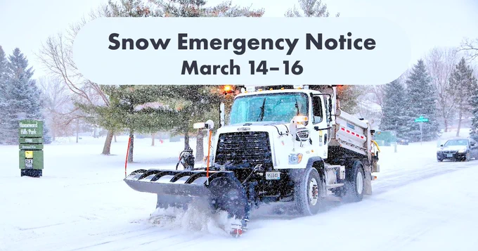 Snowplow truck clearing heavy snow on a street during a snow emergency.
