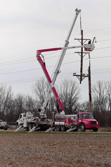2 utility bucket trucks repairing poles to restore power. 