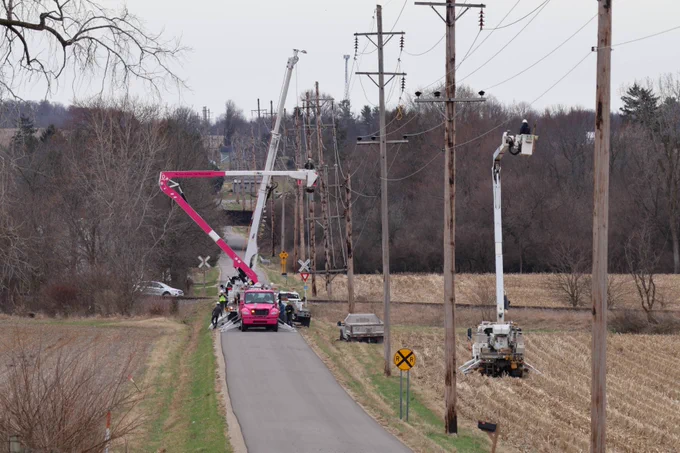 3 utility bucket trucks in a row repairing poles to restore power. 