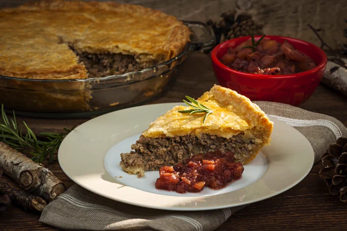 Slice of traditional pork meat pie Tourtiere with apple and cranberry chutney  