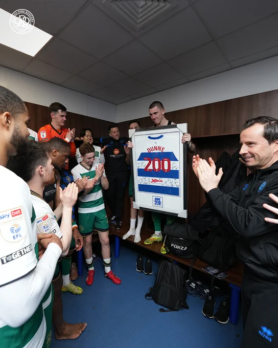 Jimmy Dunne (centre) receiving a framed signed shirt with 'DUNNE 200' on the back in the QPR dressing room.