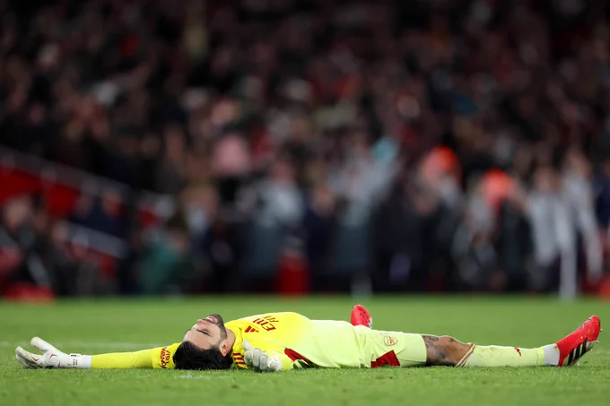 David Raya lays on his back in the middle of the pitch.
