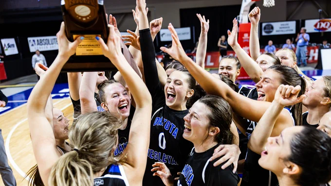The 2025-26 DWU Women's Basketball team celebrating on the court in Sioux City with their quadrant trophy, photo by ThirDWheel Photo