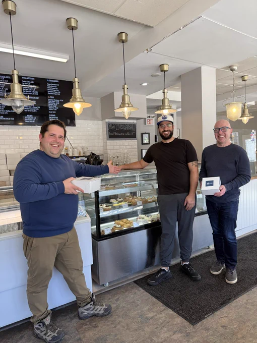 Andrew, Michael, and one of the owners of Mood Cafe (Ali) standing in front of the pastry display.