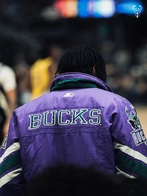 A photo of Kevin Porter Jr. from behind wearing a retro purple Bucks jacket.